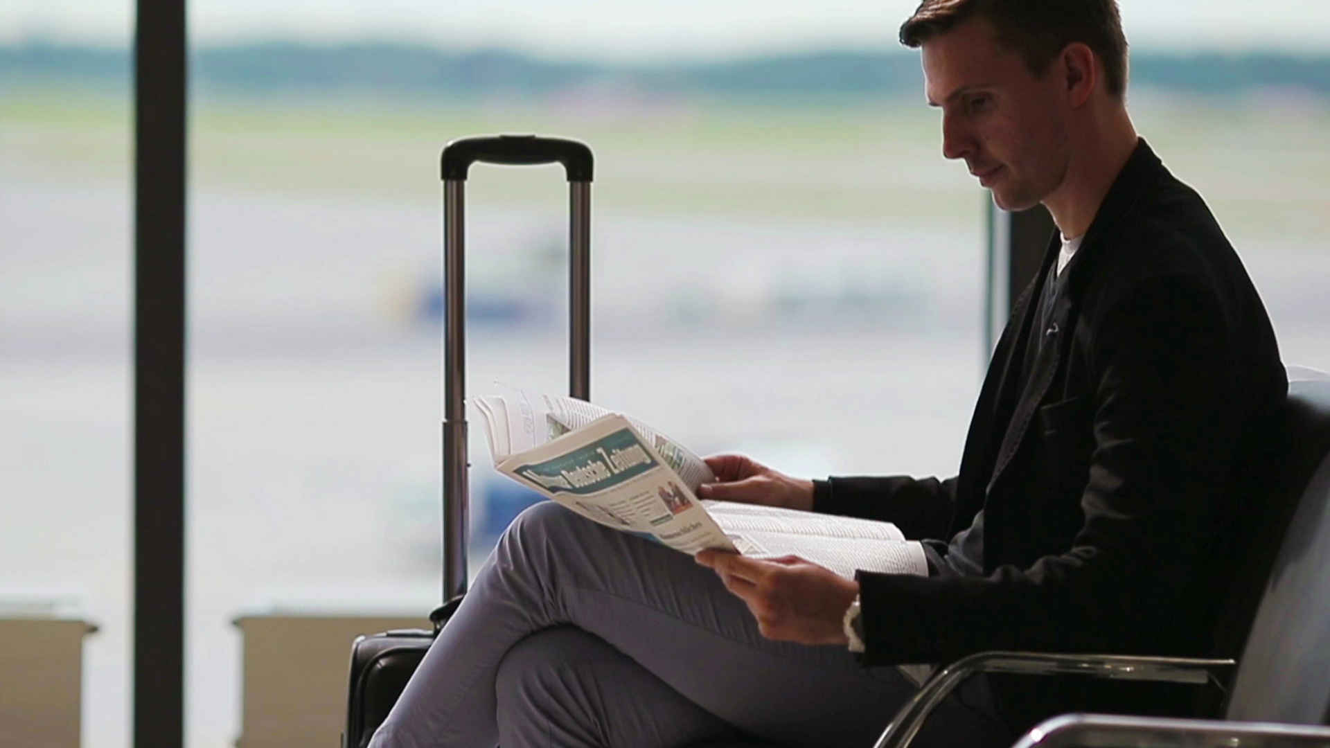 Man sitting at the airport and reading newspaper